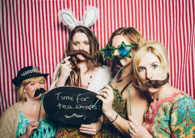 four girls in photo booth with props on striped background